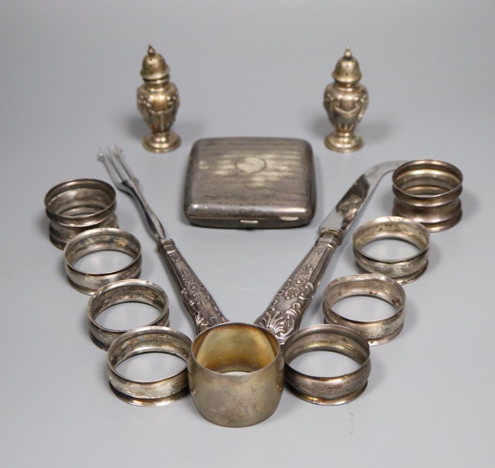 Nine assorted silver napkin rings, a pair of silver pepperettes, a silver cigarette case and pair of silver handled servers.